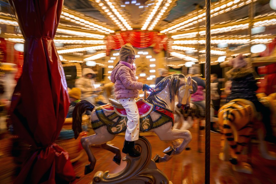 A child rides on a merry-go-round at a Christmas fair.