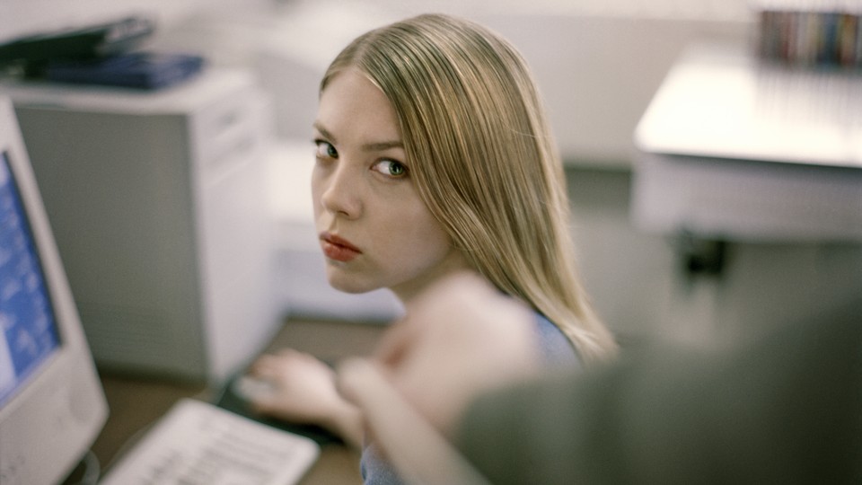 A woman in an office stares angrily at a colleague