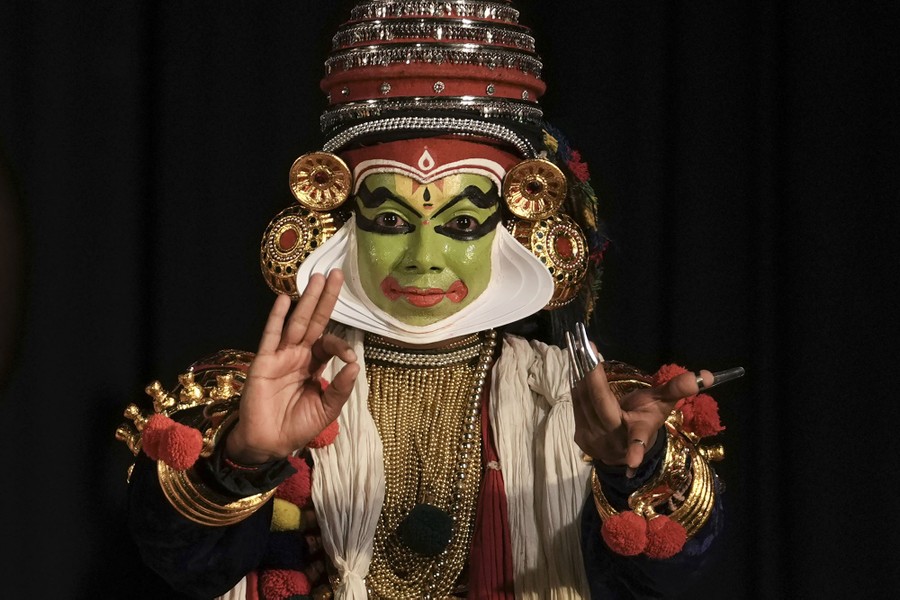 A performer poses while wearing a traditional costume and green makeup.