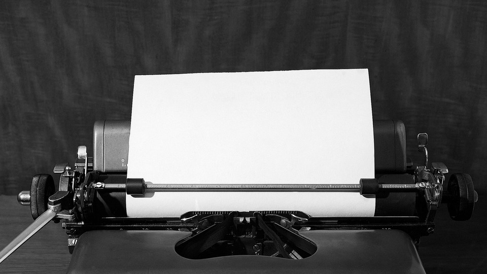 A black-and-white image of a blank sheet of paper in a typewriter