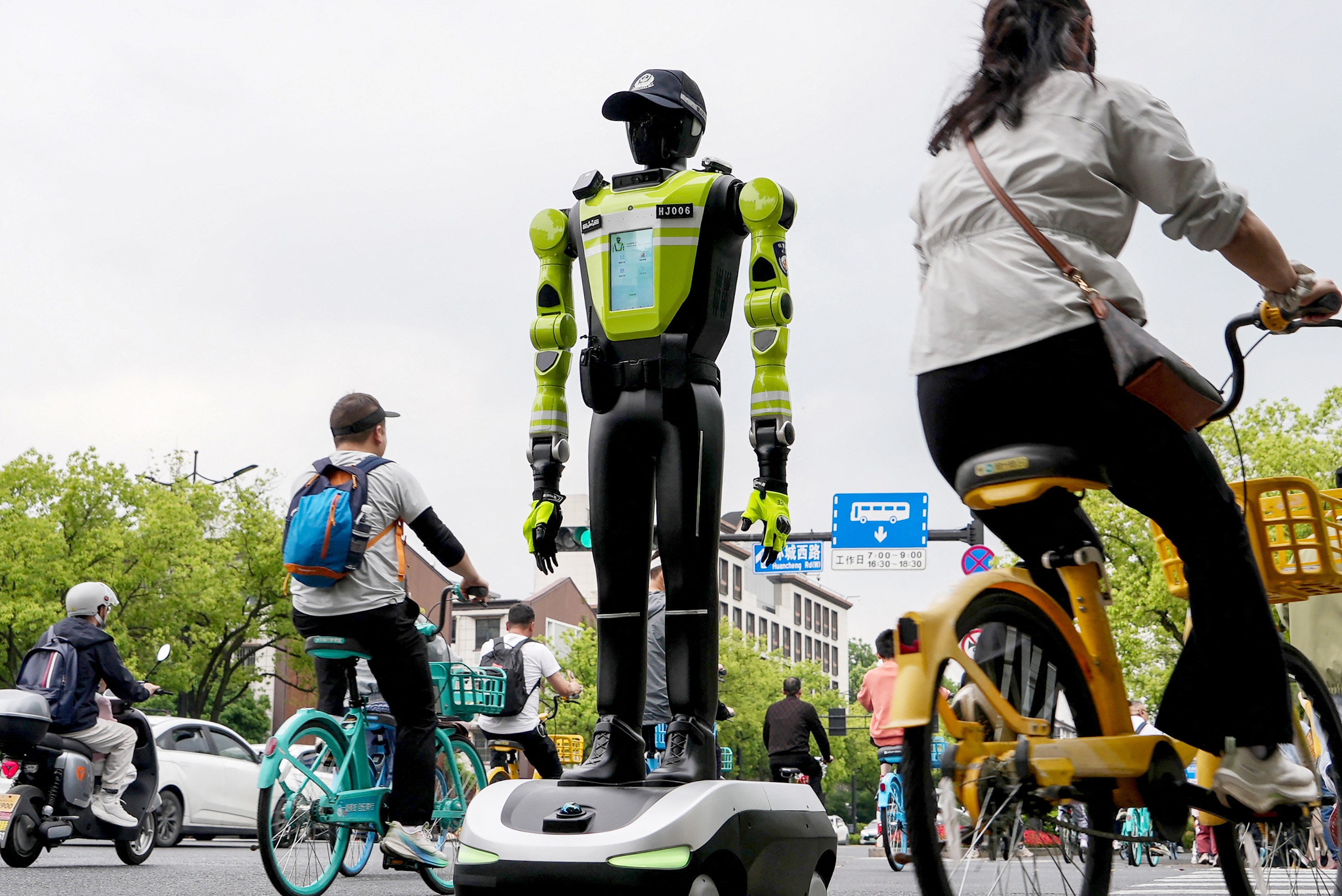 People cycle past a humanoid robot police officer in China.