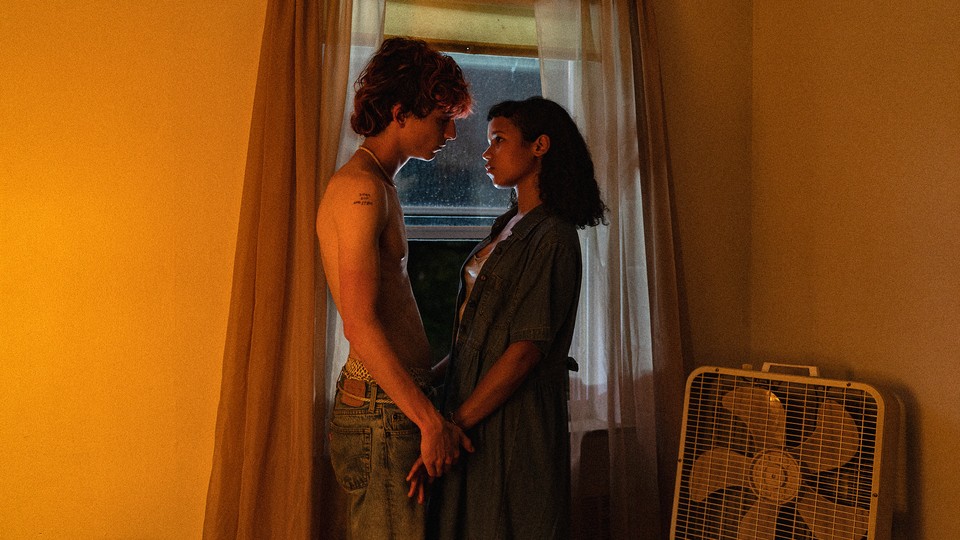 Timothée Chalamet and Taylor Russell staring into each other's eyes in front of a window in "Bones and All"