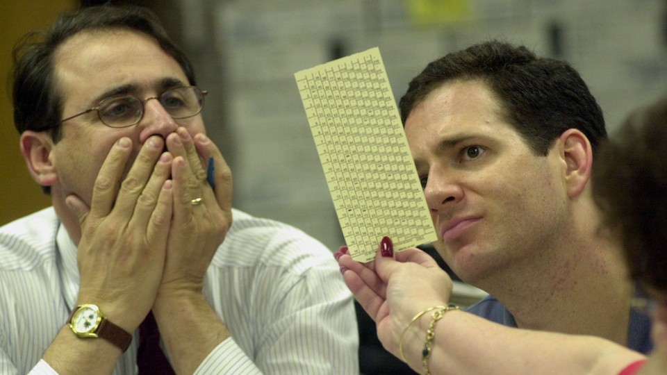 Reporters examine a ballot during a manual recount in Broward County, Florida, in 2000.
