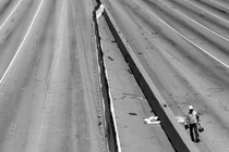 Black-and-white photo of a construction worker on an empty highway