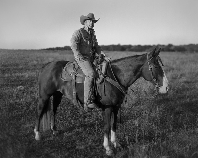 Taylor Sheridan en un caballo en un campo