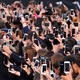 A crowd of people taking photos with smartphones