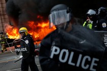 Firefighters arrive as police stand guard in front of a limousine which was set ablaze during a protest against President Donald Trump on January 20, 2017, in Washington, D.C.