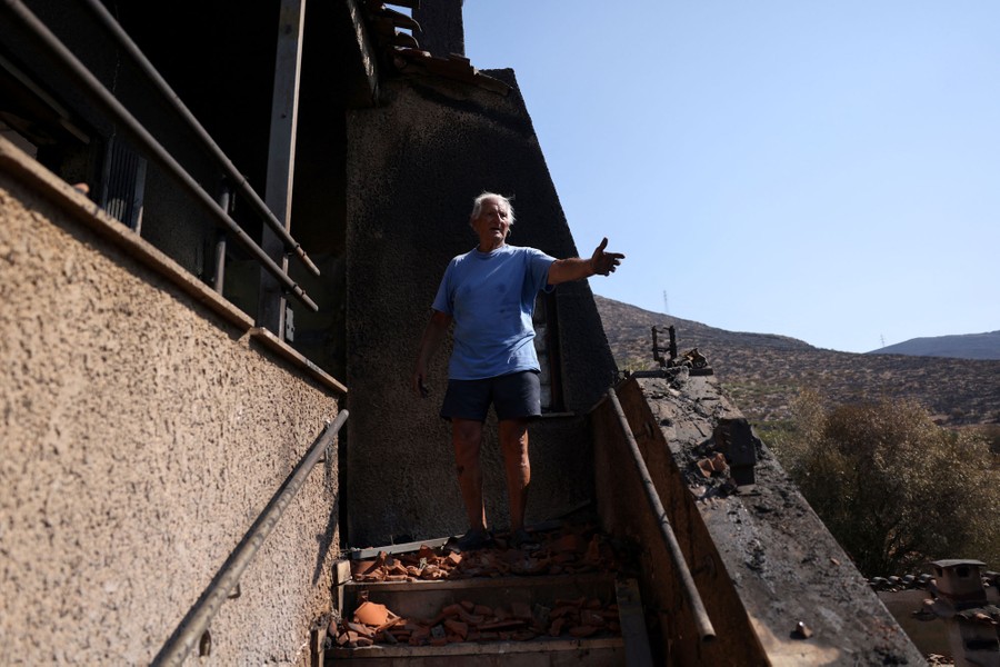A person stands on steps outside a fire-damaged house.