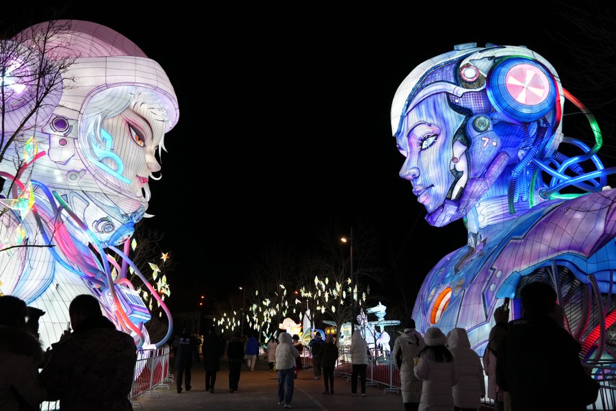 People walk past two large-scale lanterns shaped like the head and shoulders of sci-fi characters.