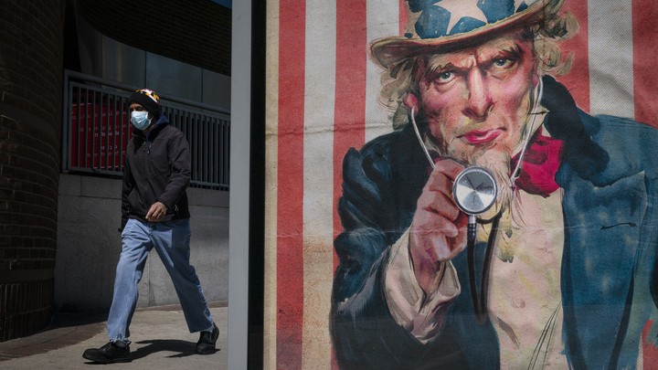 A man in a face mask walks past a bus stop in Washington, D.C.