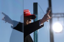 Donald Trump points his finger, and it reflects in the opposite direction on a pane of glass