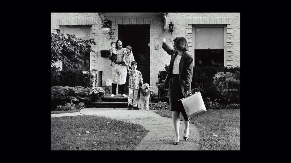 Photo of a mother leaving for work, waving goodbye to her husband and children