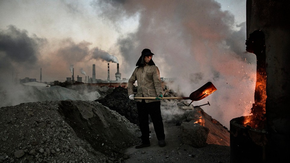 A Chinese labourer loads coal into a furnace as smoke and steam rise from an unauthorized steel factory on November 3, 2016, in Inner Mongolia, China.