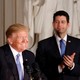 President Donald Trump smiling while Paul Ryan and Mitch McConnell clap