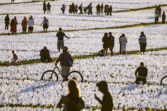 People walk through the flags of the "In America: Remember" public art installation on the National Mall near the Washington Monument on September 26, 2021, in Washington, D.C