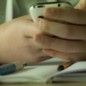 a child's hands hold a smartphone at school