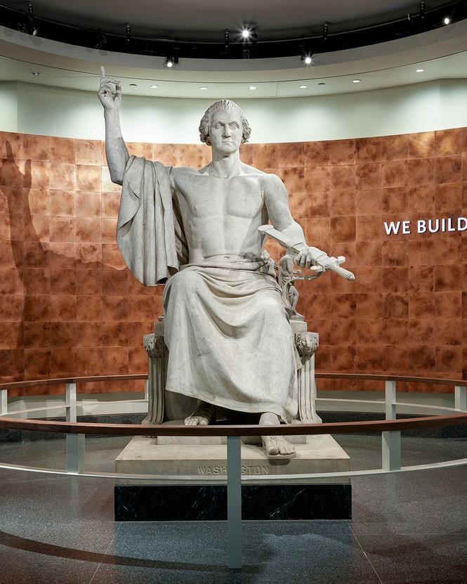 A photograph of a sculpture of George Washington seated, and with a ripped physique