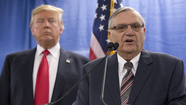 Joe Arpaio speaks with President Trump behind him.
