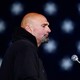A photograph of John Fetterman in profile standing in front of a microphone