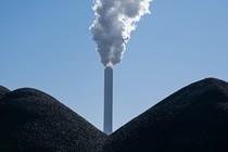 A smoking smokestack stands behind piles of coal at the coal-fired Onyx Kraftwerk Farge power plant.