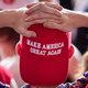 person with his hands on his head, wearing a red MAGA cap