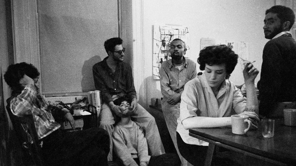 A black and white photo of writers sitting around at a party smoking and drinking