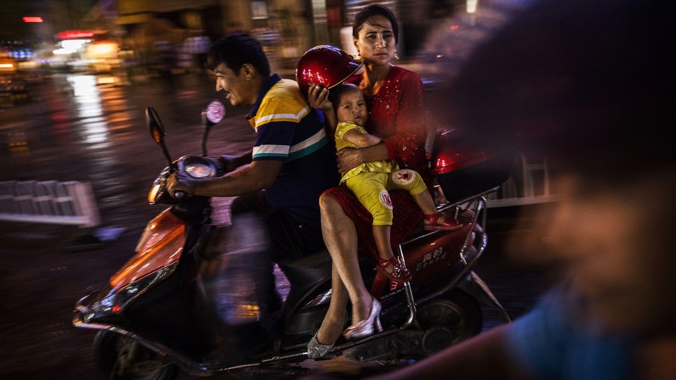 A Uighur family rides a scooter through Kashgar, Xinjiang, China, in 2017