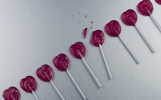 a photo of heart-shaped lollipops in a row, with one that's broken in the middle