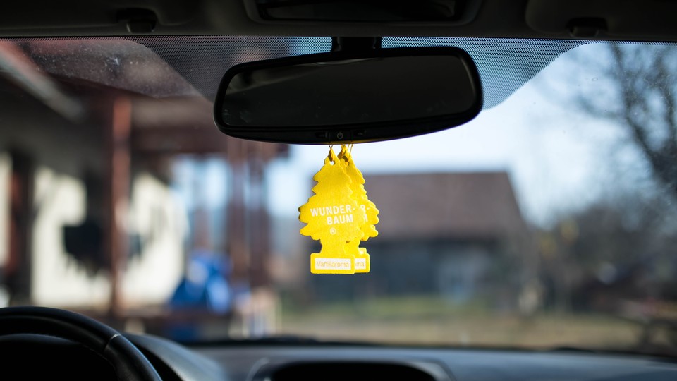 Two yellow air fresheners hang from a car mirror