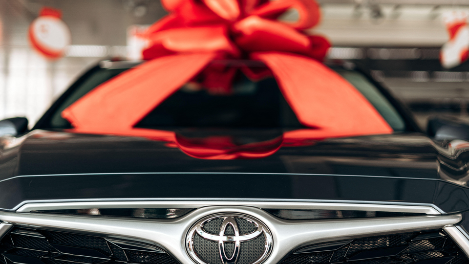 An image of a Toyota car with a red bow on the hood.