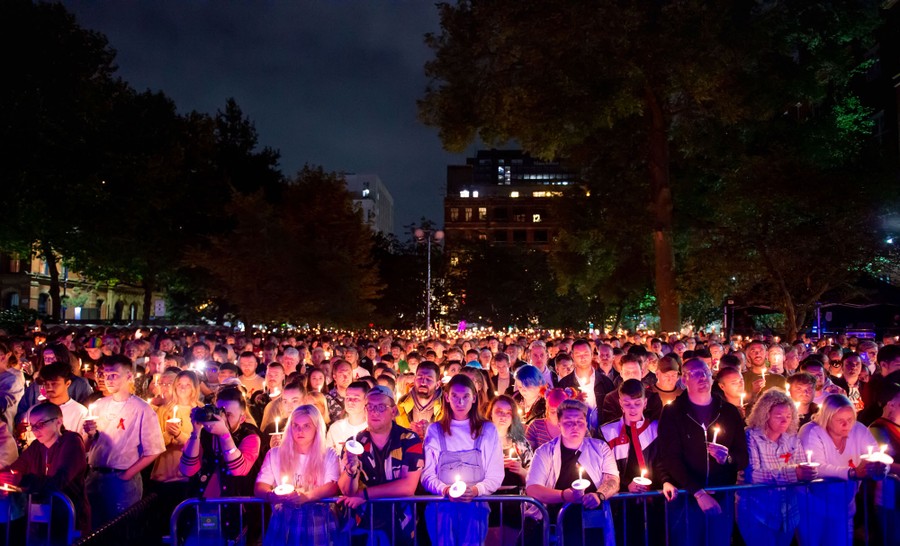 A crowd of people stand together holding candles.