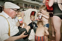 Grandparents drinking sodas with kids eating chips at the beach