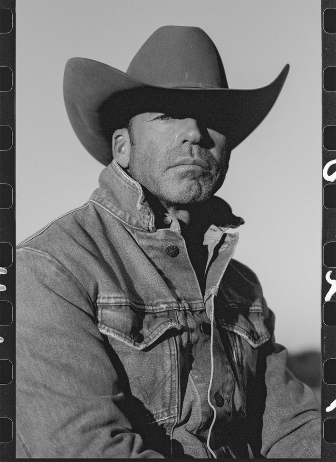 Une photographie de Taylor Sheridan sur un cheval dans un champ.