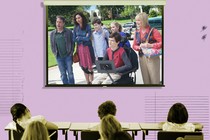 A frame from the ABC show "Speechless" is superimposed on a projector screen in a classroom.