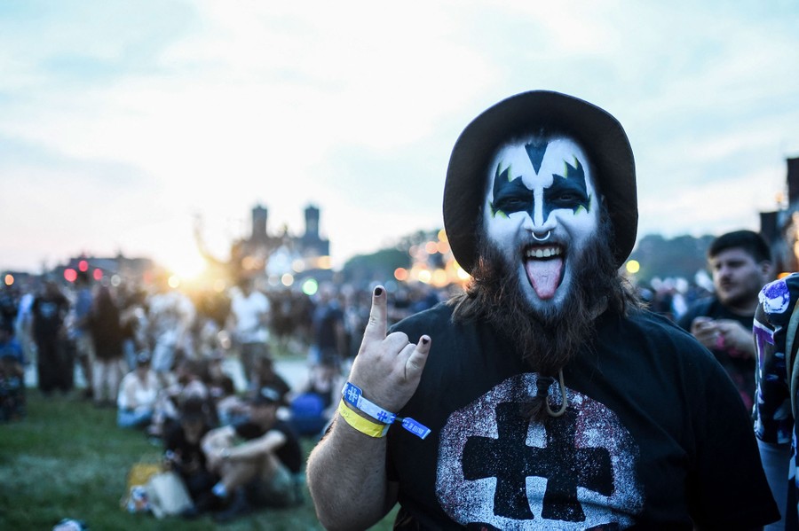 A fan wearing black-and-white makeup poses for a photo at an outdoor concert.
