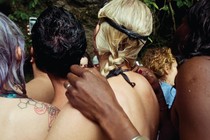 Four people photographed from behind, hugging each other