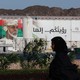 A woman walking past portrait of Sultan Qaboos