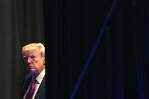 Photograph of Donald Trump peering out from behind a curtain