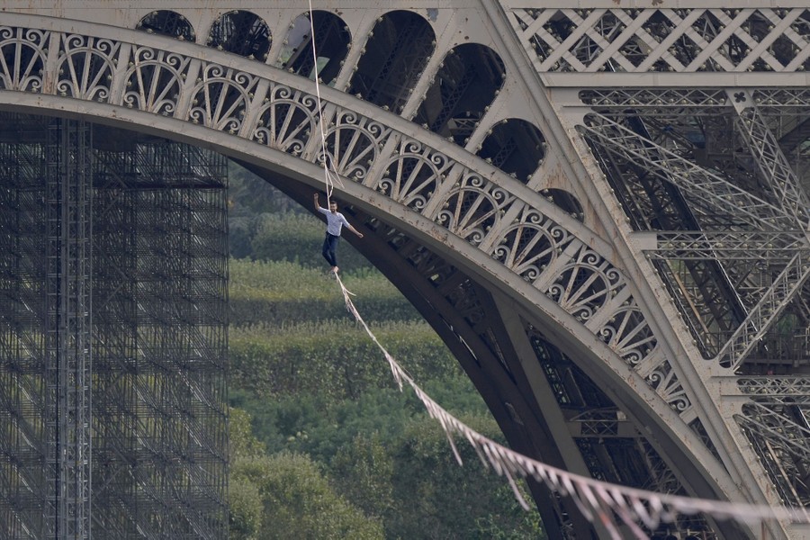 A man walks a slackline attached to the Eiffel tower