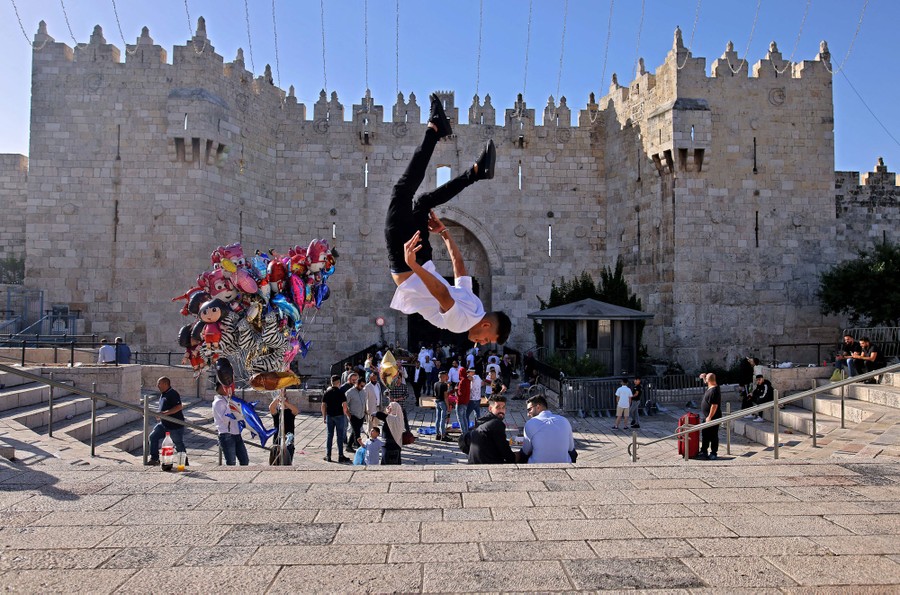 A young man performs a flip in a courtyard.