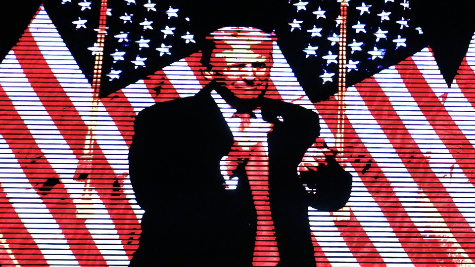 Trump standing in front of two American flags