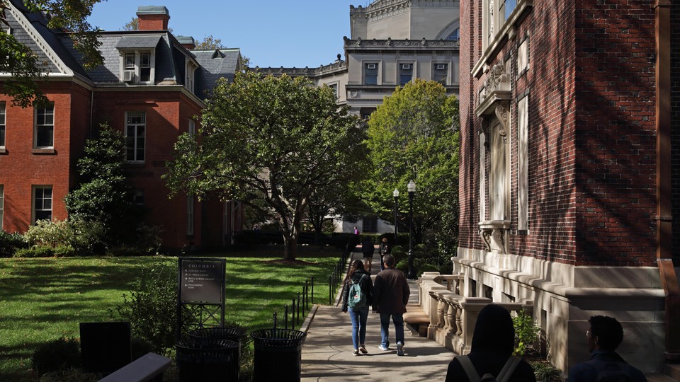 A color photograph of brick buildings and a green lawn on Columbia University campus in Morningside Heights, New York.