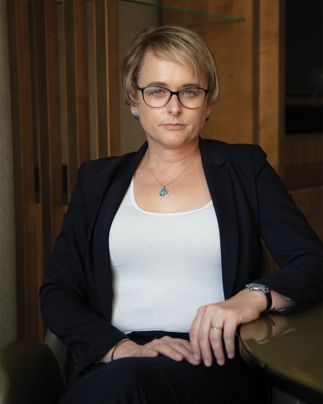 a portrait of the author, Julia Curlee, seated at a table, wearing a white blouse and a dark suit