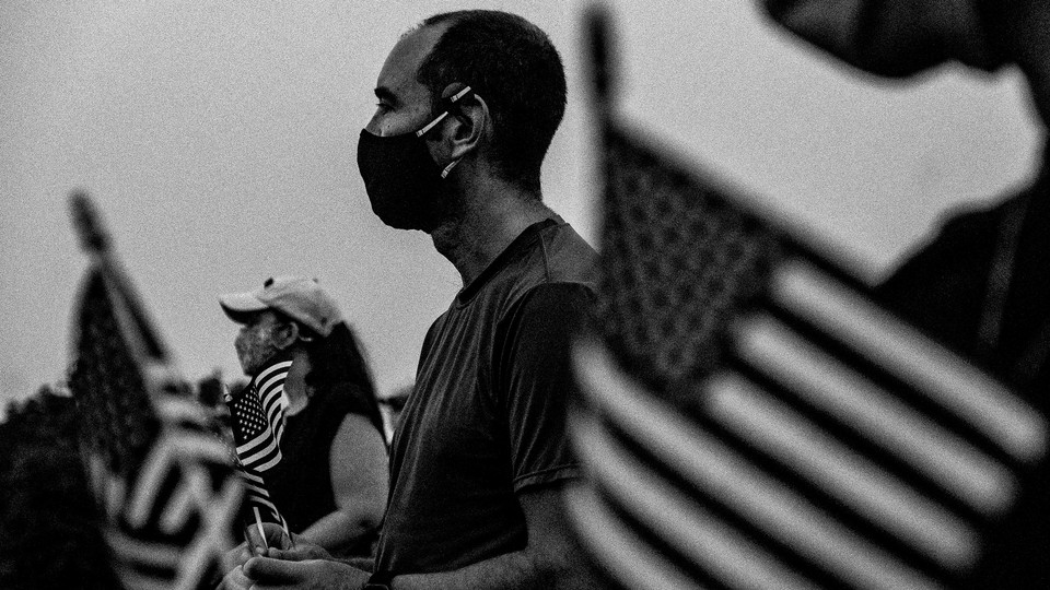 Photograph of people gathering in Washington, D.C., holding American flags, to honor those who died from COVID