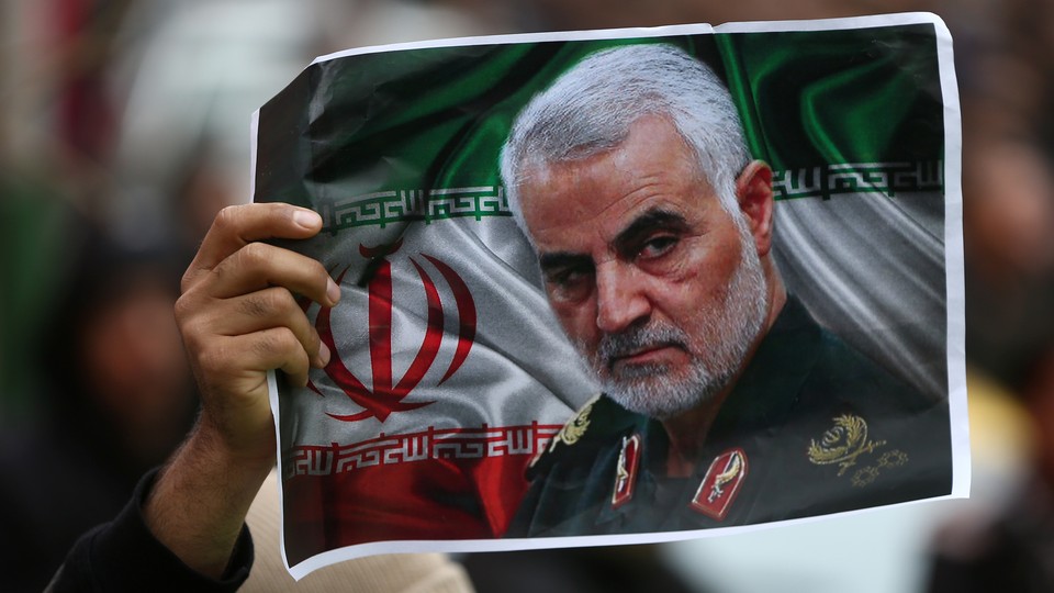 A protester holds up a picture of late General Qassem Soleimani.