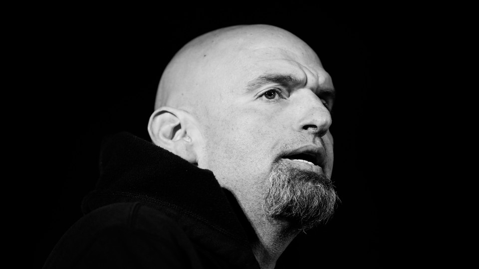 A black-and-white photo of John Fetterman, Pennsylvania candidate for U.S. Senate, against a black backdrop