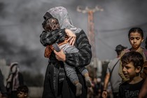 A mother covers her child's face to protect it from the smoke as Palestinians flee the northern part of Gaza to the central and southern parts, on November 10, 2023.