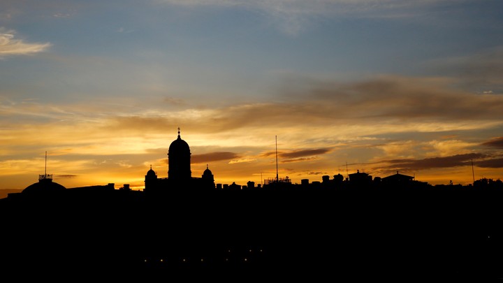 The sun sets behind the Presidential Palace and the cathedral in Helsinki.