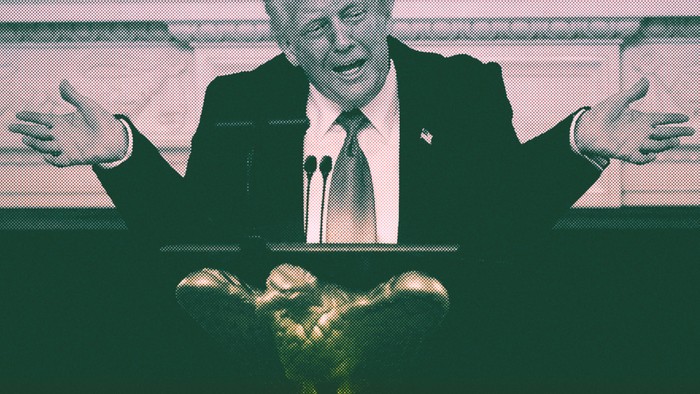 Donald Trump throws up his arms in front of a podium