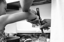 A child cooks with the help of an adult.